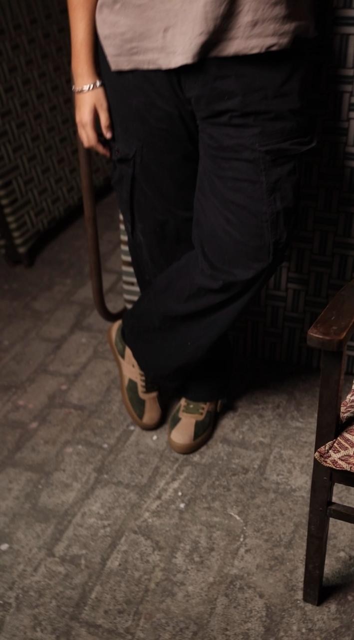 Green and beige CHRN sneakers styled with black trousers